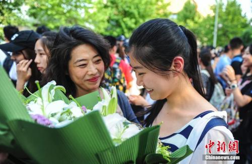 資料圖：山東濟(jì)南眾多考生手捧鮮花在家長(zhǎng)的簇?fù)硐職g快告別高考。中新社記者 張勇 攝