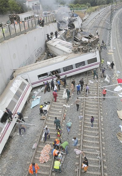 24日，救援人員在西班牙列車(chē)脫軌現(xiàn)場(chǎng)。一節(jié)車(chē)廂被強(qiáng)大的慣性?huà)伾翔F道邊的高臺(tái)。