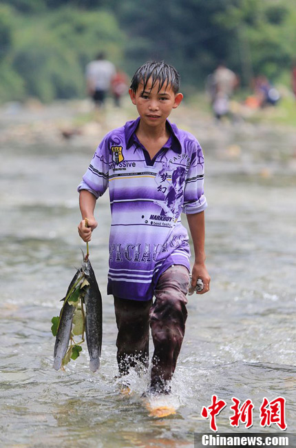 圖為7月9日，一名男孩在鬧魚節(jié)活動中抓到了兩條魚。譚凱興 攝