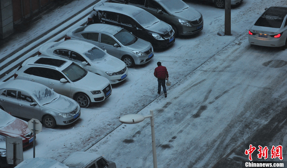 11月18日，行人在沈陽(yáng)街頭的積雪中穿行。