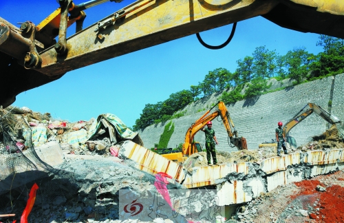 為確保道路盡早通車，工人師傅冒著烈日，指揮施工機械清理爆破現(xiàn)場