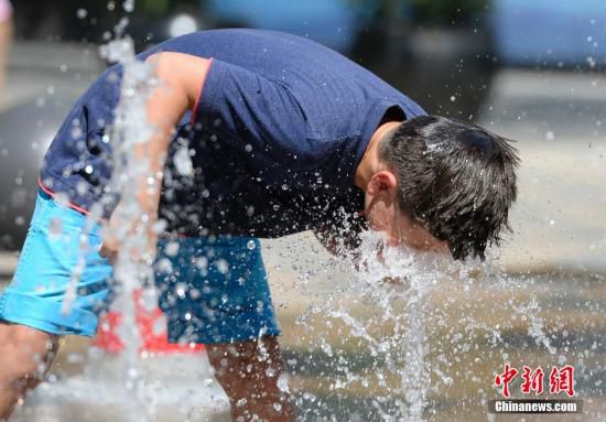 5月29日，一名小孩將頭伸向北京街頭的噴泉以降溫祛暑。