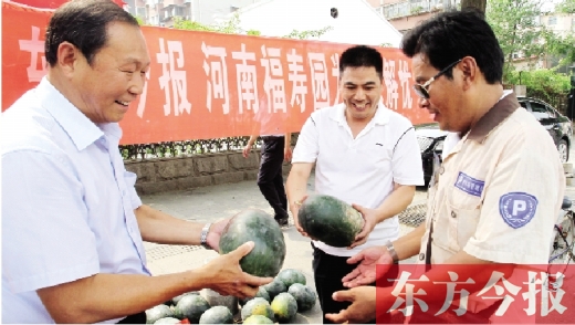 河南福壽園區(qū)域總經(jīng)理吳正宗（左一）、東方今報發(fā)行中心副總監(jiān)王路喜（中）在街頭給市民送瓜