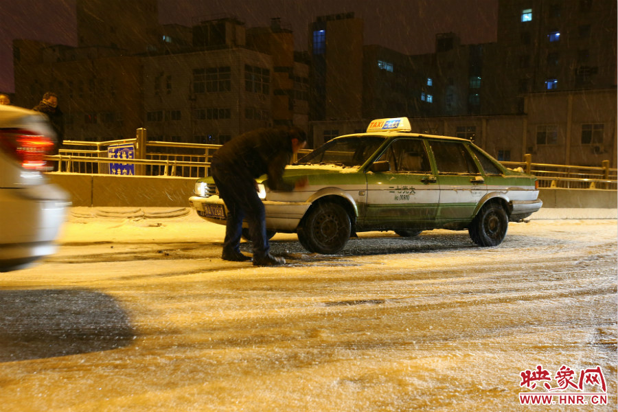 一位出租車司機(jī)在車輪前灑上雪，希望能增加輪胎的摩擦力。