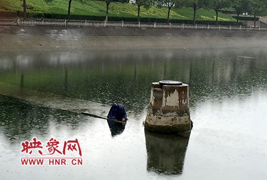 一女子穿著雨披獨自站在東風(fēng)渠中