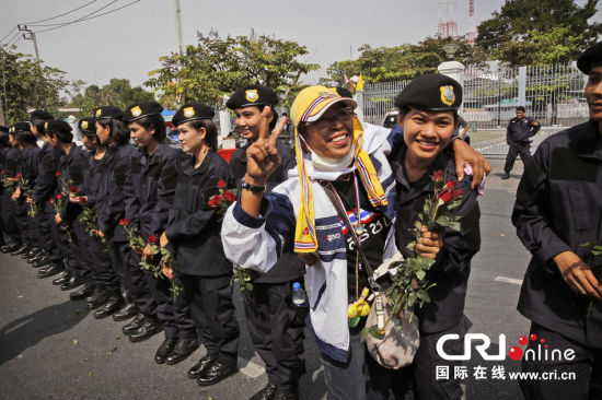 2013年12月03日,曼谷總理府與曼谷警署允許反政府示威民眾進入,雙方進入暫時“停戰(zhàn)”狀態(tài)迎接泰王生日。曼谷警察總署,女警們手持鮮花送給反政府示威民眾。圖片來源:Manish Swarup/東方IC