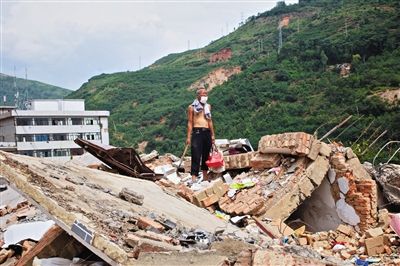 8月9日,龍頭山鎮(zhèn),一位老者在自家房屋廢墟上尋找家當(dāng)。