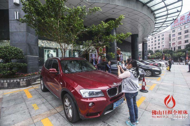 一輛停在停車位上的寶馬轎車，被墜落的樹枝砸中，樹枝徑直插入車內(nèi)，現(xiàn)場(chǎng)引發(fā)不少市民圍觀拍照。