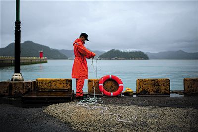 7月6日，韓國珍島，一名海岸警察在港口系救生圈。4月，客輪在珍島近海發(fā)生沉船事故后，仍有11人下落不明。