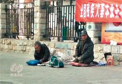 工人體育場北路，兩位乞討者路邊乞討，并輪流扮成“病人”（躺地者）。 央視截圖