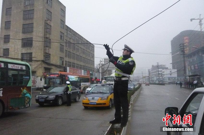 安徽一交警雨中托舉電纜讓車輛通過(guò)