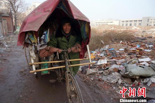 圖為老人走出窩棚，推著三輪車(chē)準(zhǔn)備出去撿拾廢品。周小云 攝